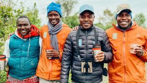 Group photo including a Maasai Tribe member, a Nat Hab Expedition Leader and local guides. Nat Hab’s Mara East Camp—Mara Conservancy, Maasai Mara National Reserve.