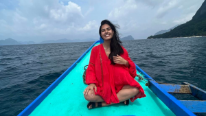 Author in red dress smiling on blue boat in body of water