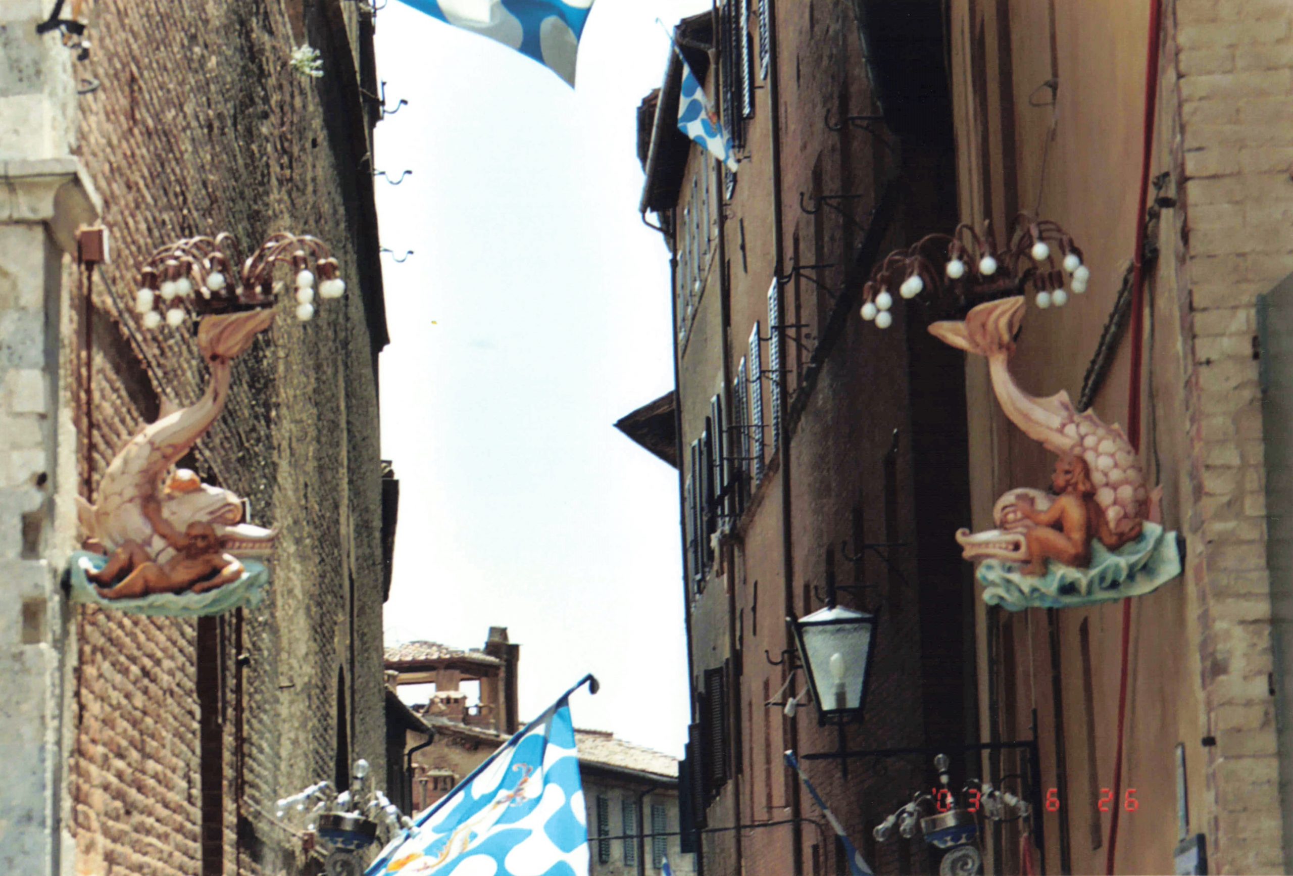 fish-shaped lanterns hanging above the colorful flags of Siena’s 17 contrade (districts), proudly flown in anticipation of July’s Palio, a centuries-old bareback horse race.